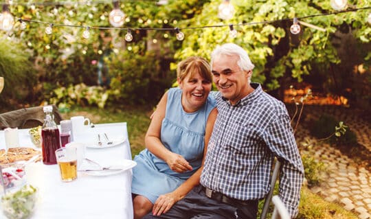 Senior couple sitting at table outside in yard