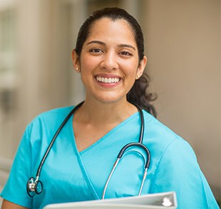 A nurse smiles in blue scrubs